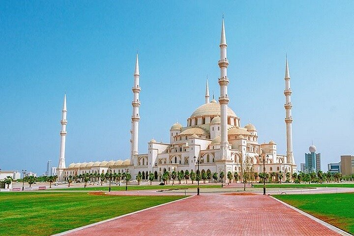 Majestic white minarets rise against a clear blue sky inviting visitors to explore the stunning architecture and serene surroundings of the Sheikh Zayed Mosque on Fujairah's east coast.
